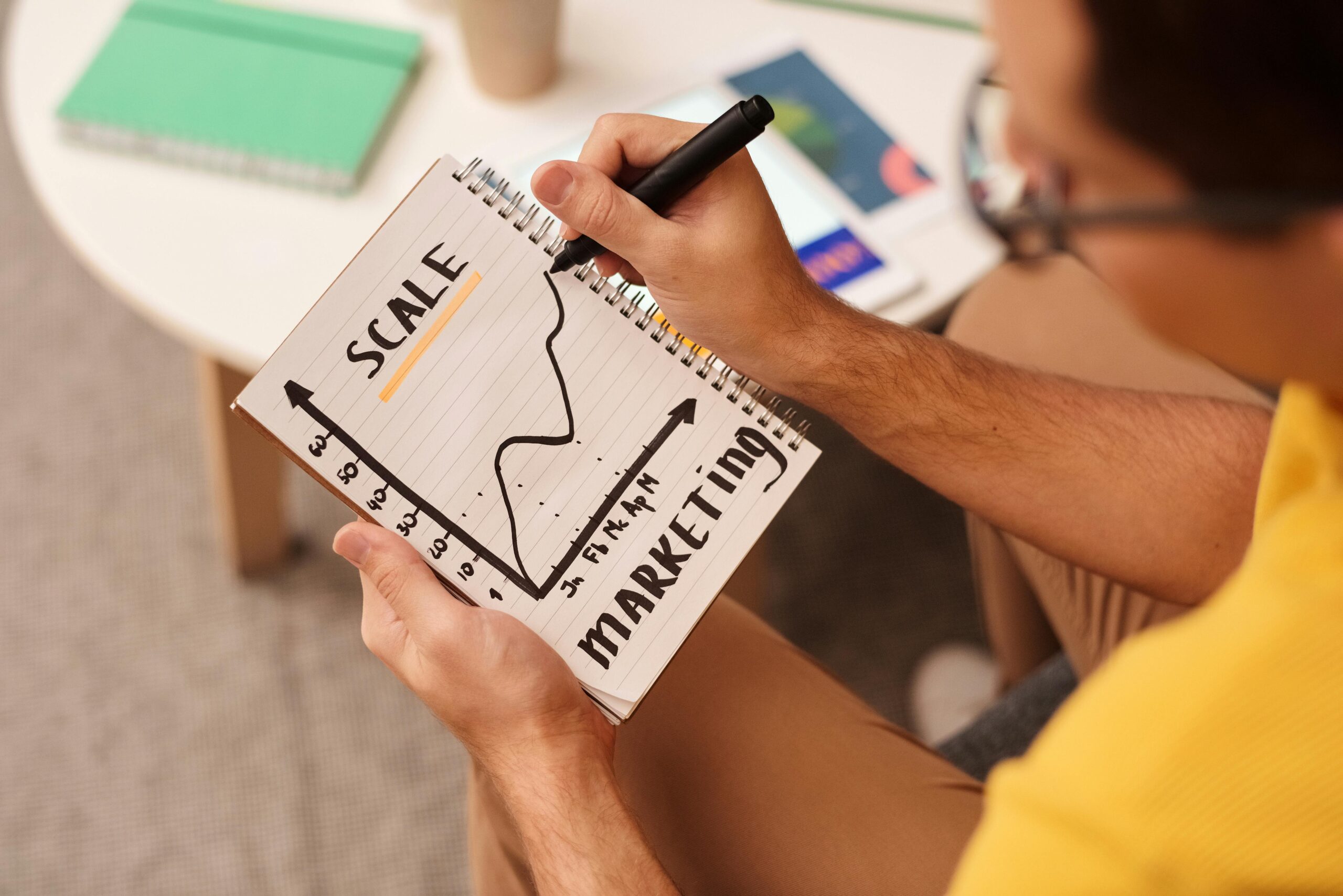 A man drawing a business scale graph on a notebook